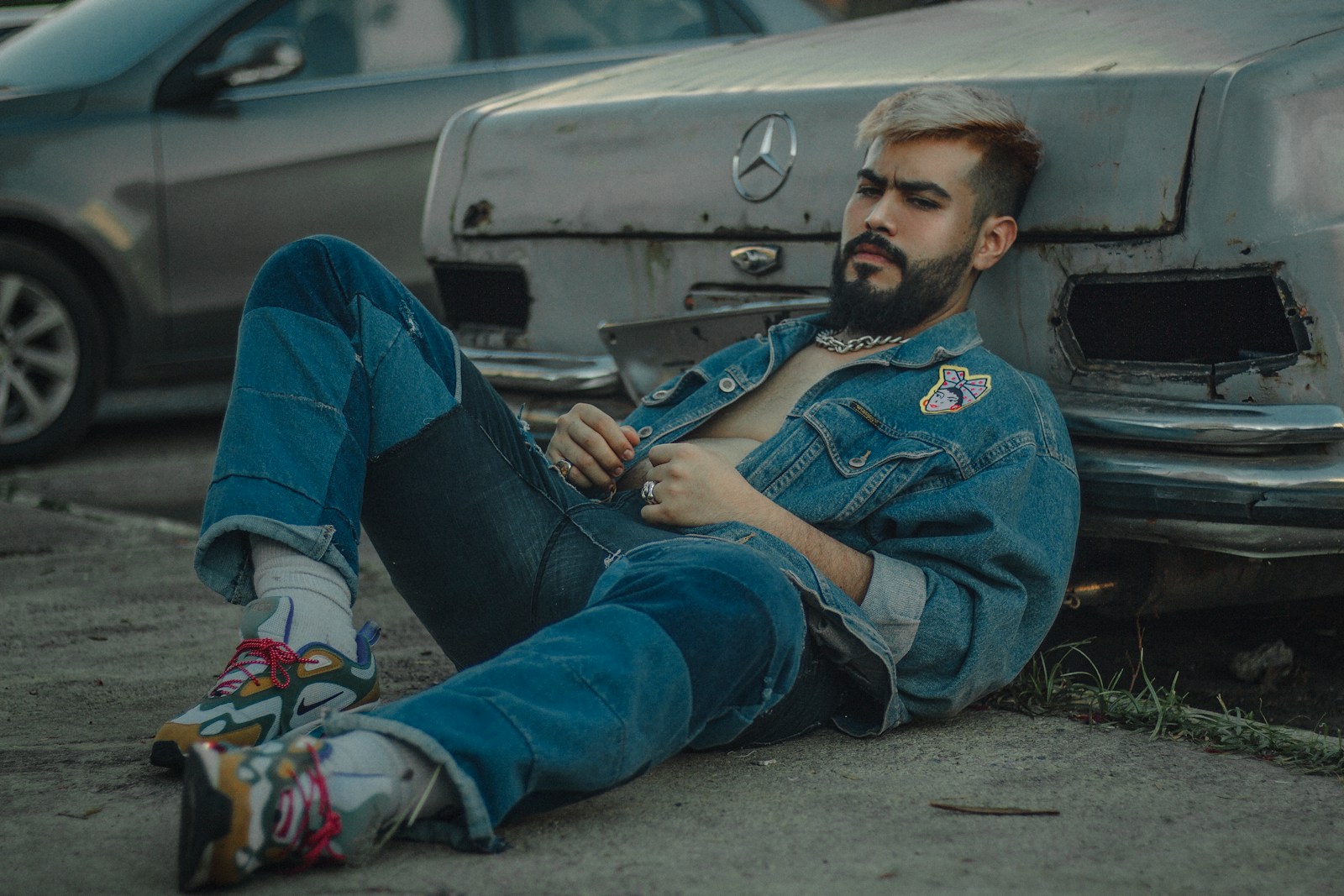 a man sitting on the ground next to a car